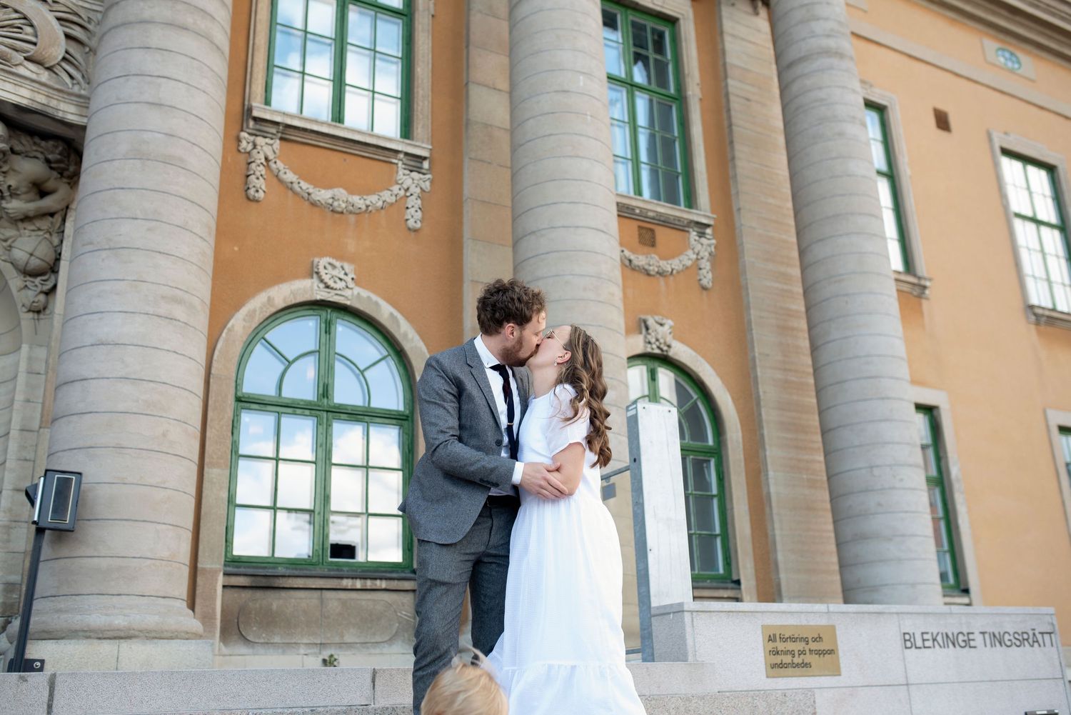 Romantic moment captured in front of historic building with columns.