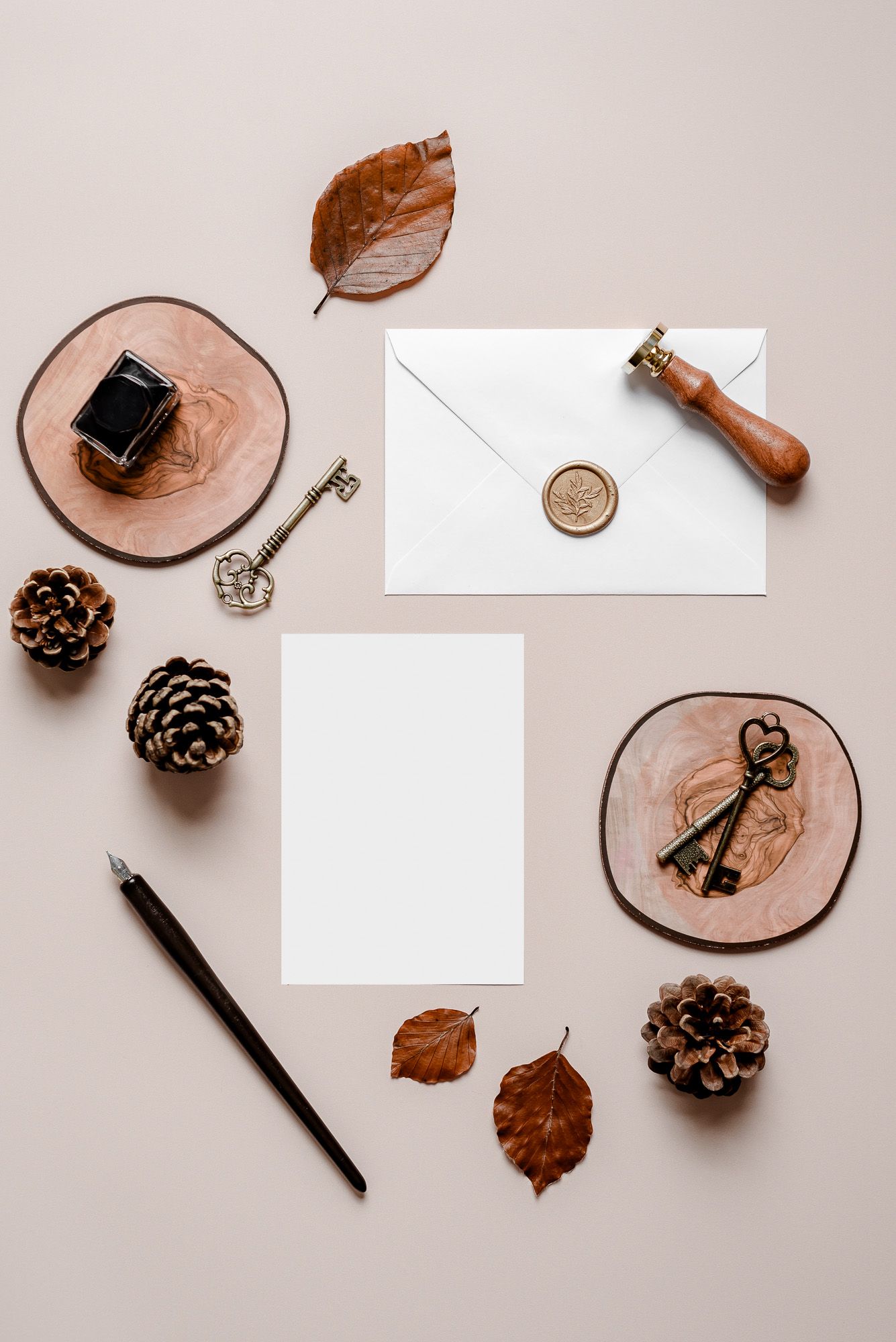 Invite and envelope mock-up on a beige backdrop with ink stamp and autumnal leaves surrounding. Wedding, fall, cozy,
