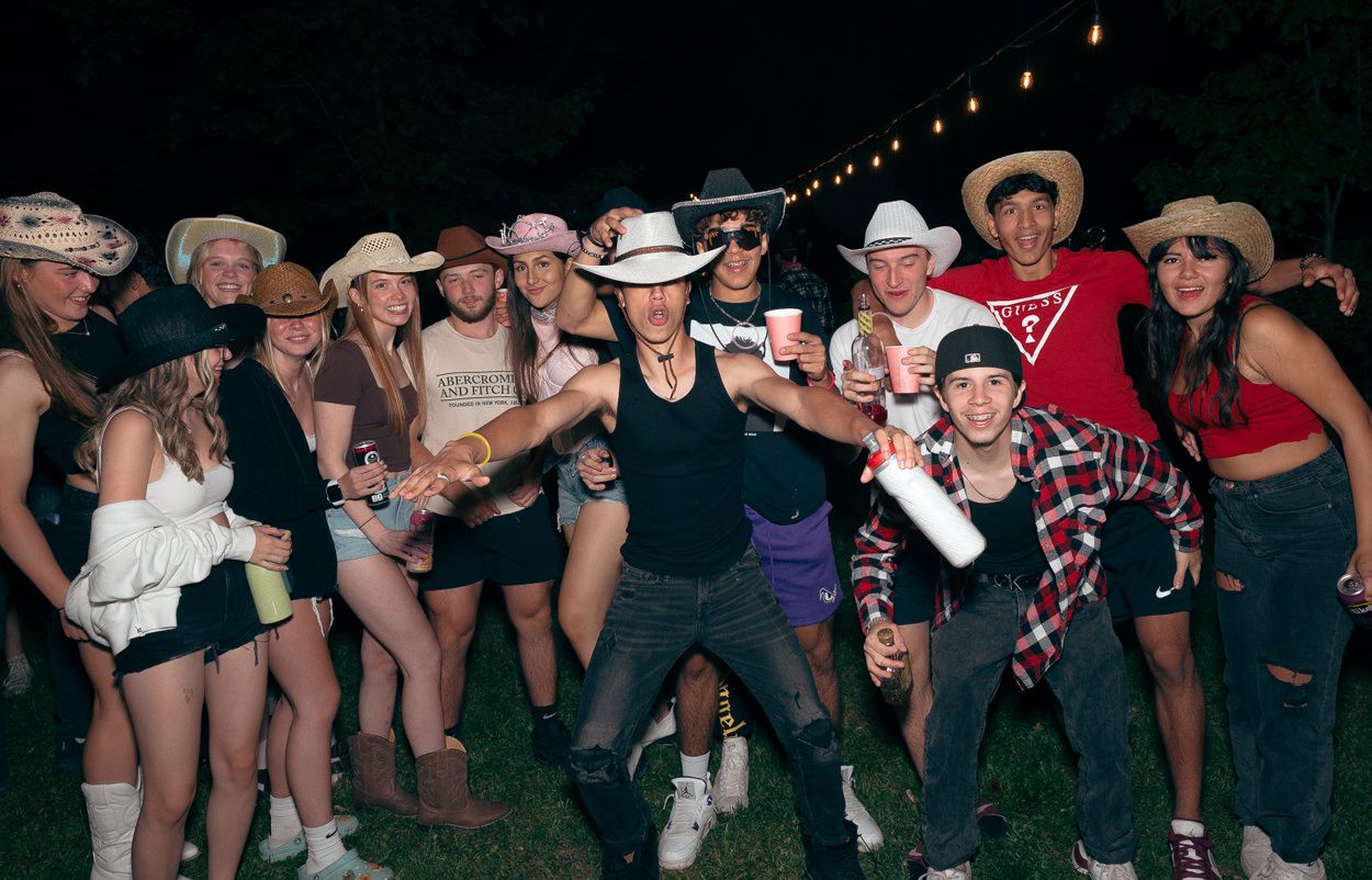 Crowd of partygoers in western attire celebrate together at a nighttime outdoor gathering.