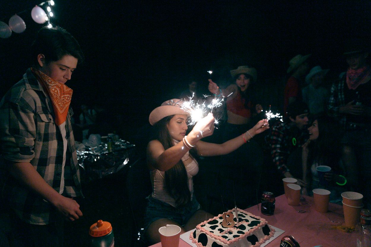 Sparklers light up a nighttime celebration around a birthday cake at an outdoor party.