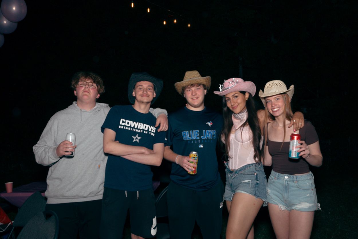 Friends gather for a group photo at a western-themed party wearing casual attire.