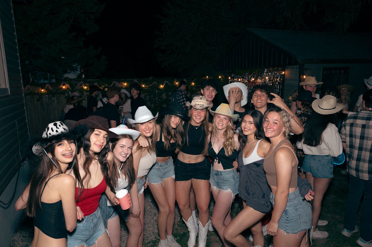 Group of friends in western attire and cowboy hats enjoying a nighttime outdoor party.