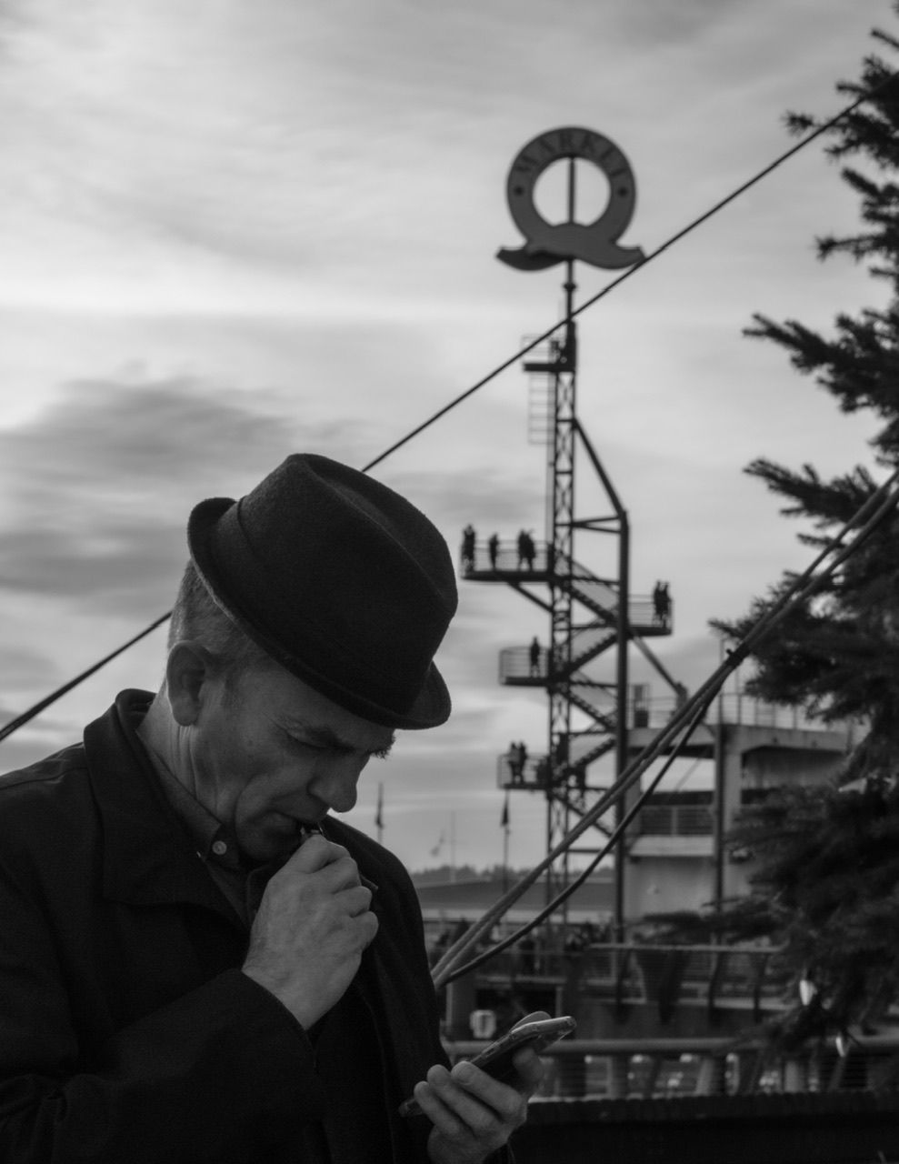 Black and white portrait of man with hat beside communications tower, North Vancouver photographer