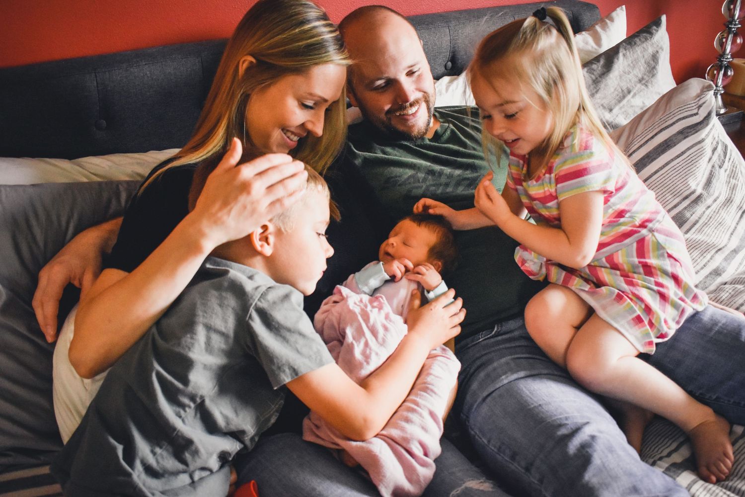A family lies together on a couch, sharing an intimate moment with their newborn baby.