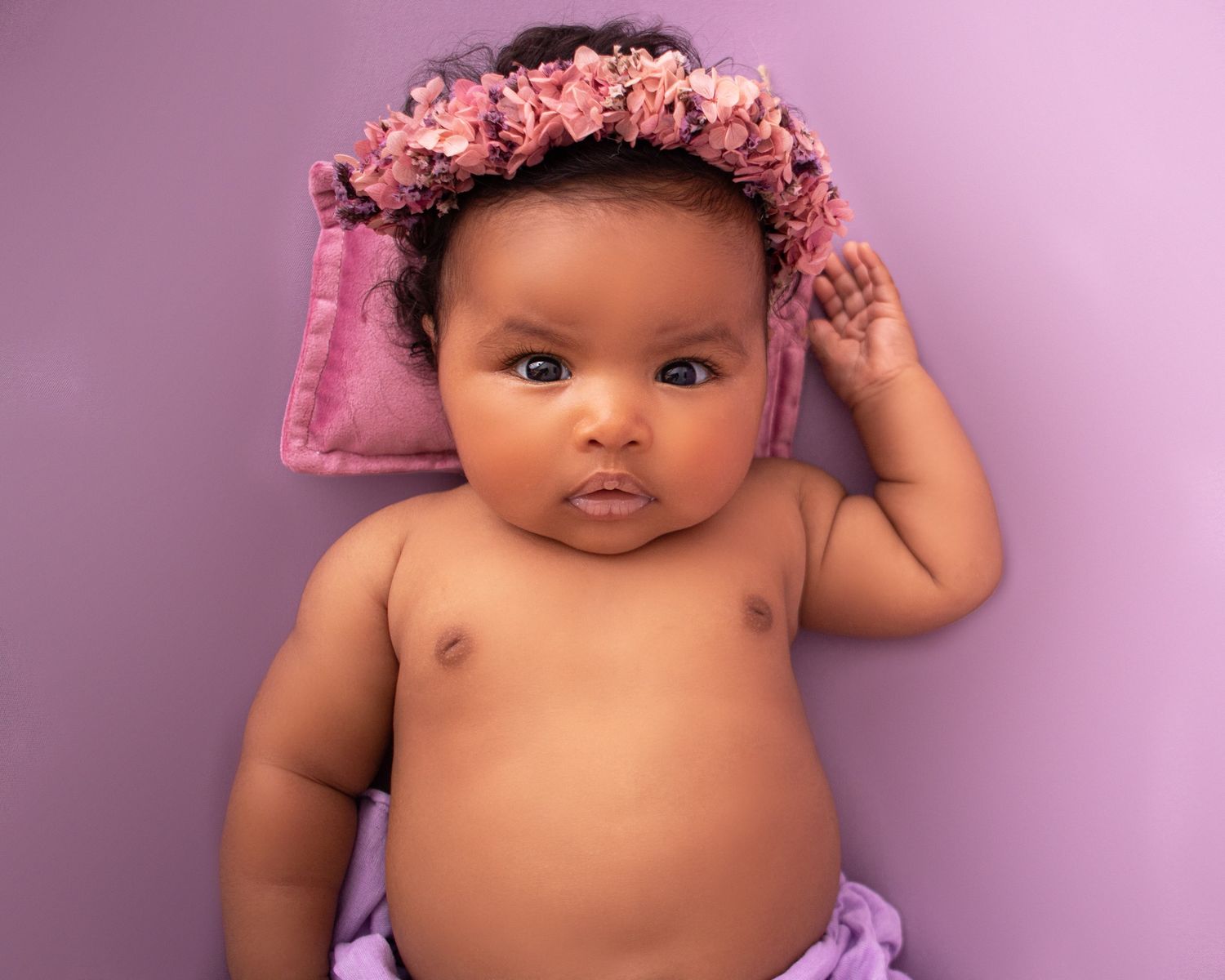 baby girl on purple backdrop with flower headband photographed by newborn photographer swansea