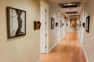 Long carpeted corridor in medical facility with white walls and recessed lighting.