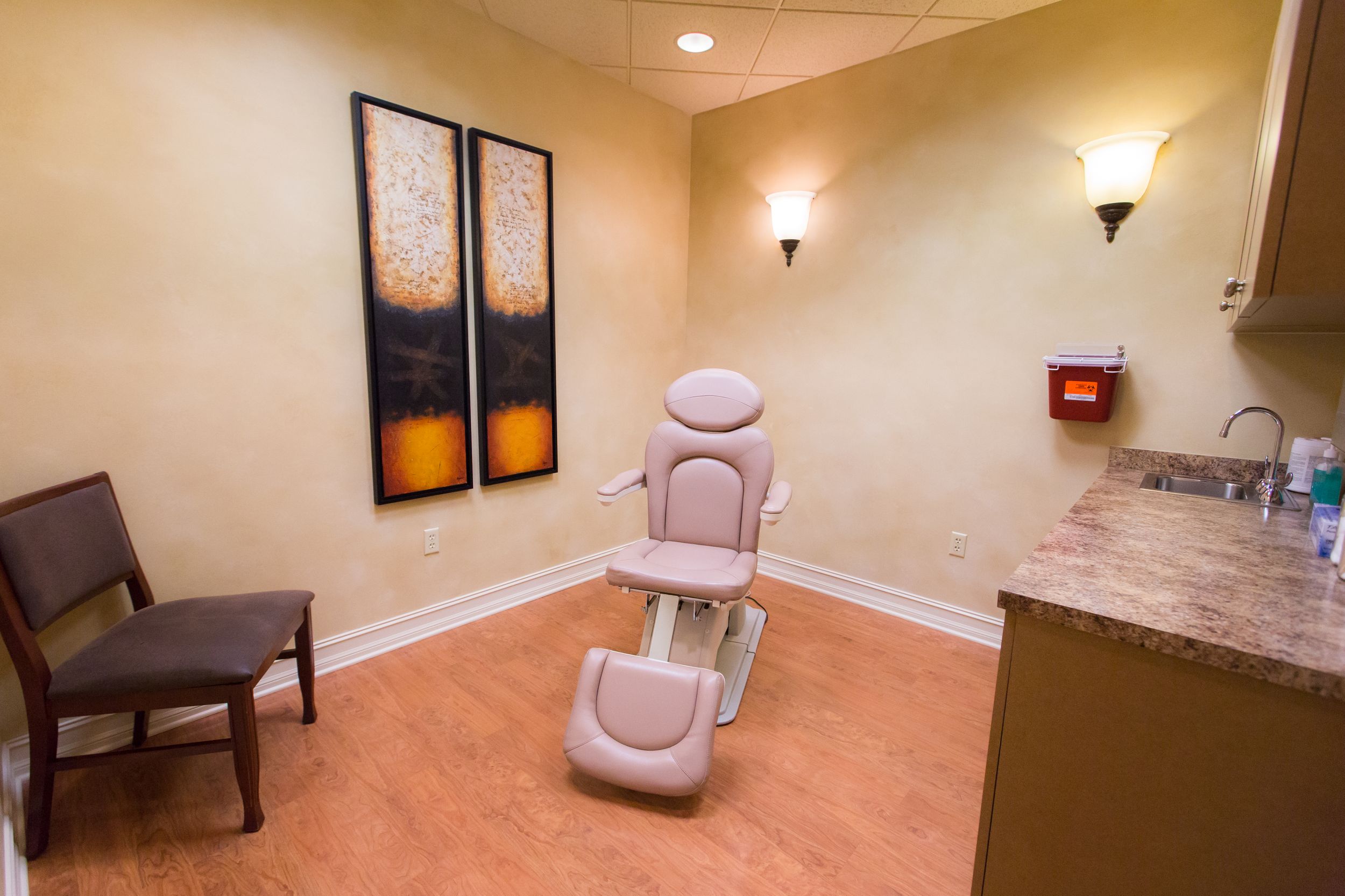 Patient treatment room with medical equipment and comfortable seating.
