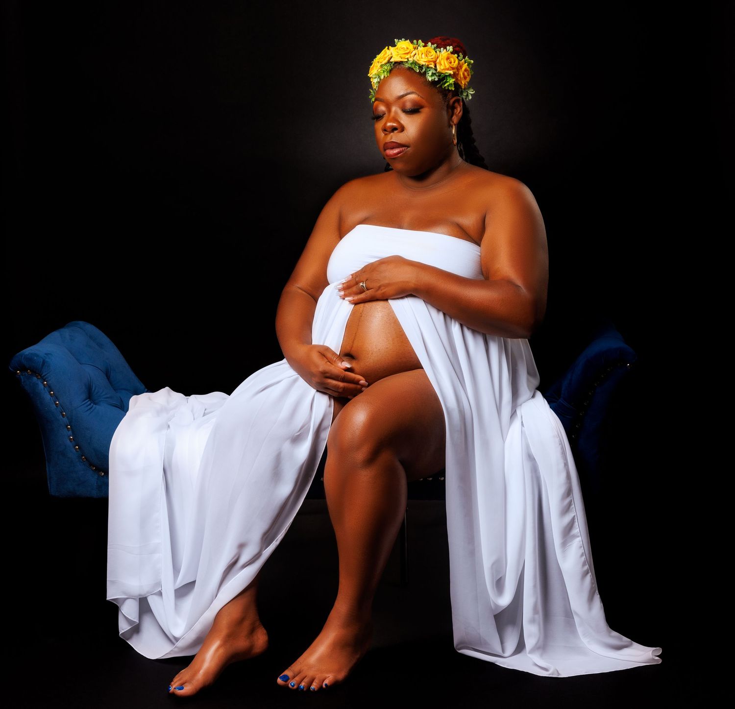 Maternity Portrait wearing White Dress on a blue couch in studio