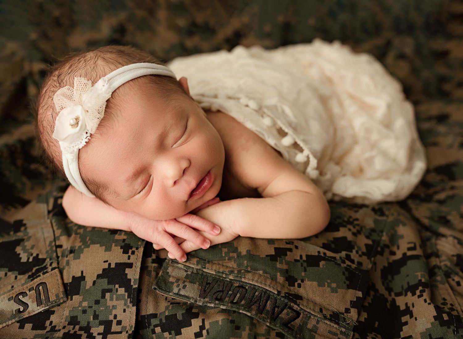 newborn photos for military families, baby girl in cream lace asleep on military uniform