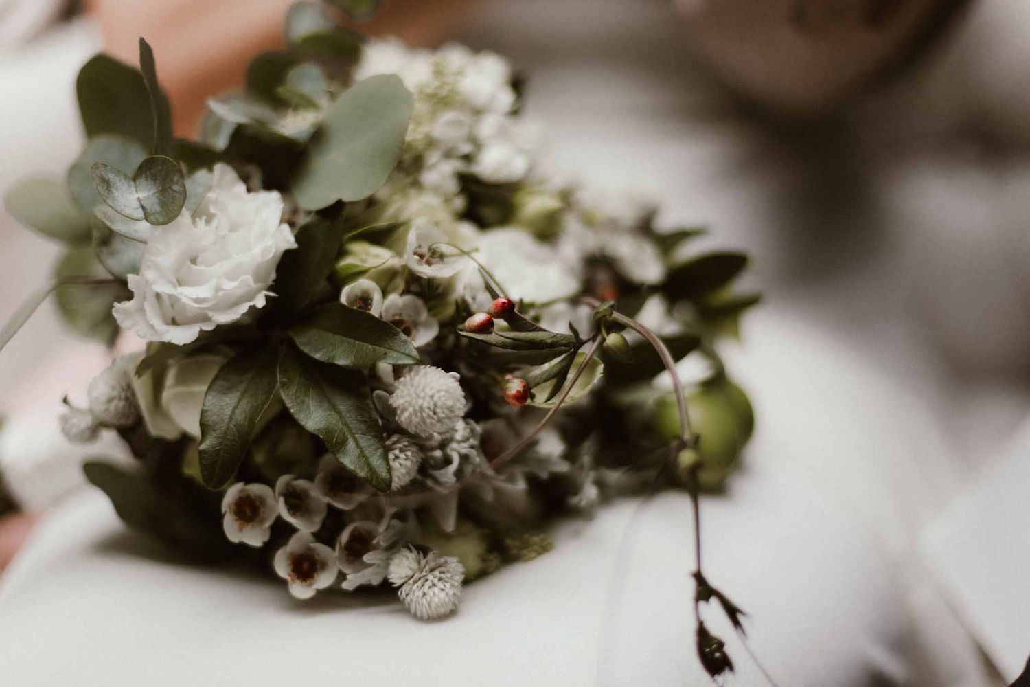 Elegant wedding bouquet with white flowers and eucalyptus leaves in soft focus.