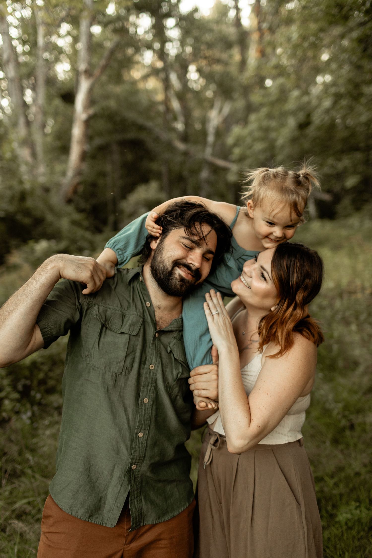 Family plays together outdoors in a wooded setting during golden hour.