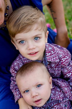 Two siblings wearing matching patterned shirts pose together for a close-up portrait.