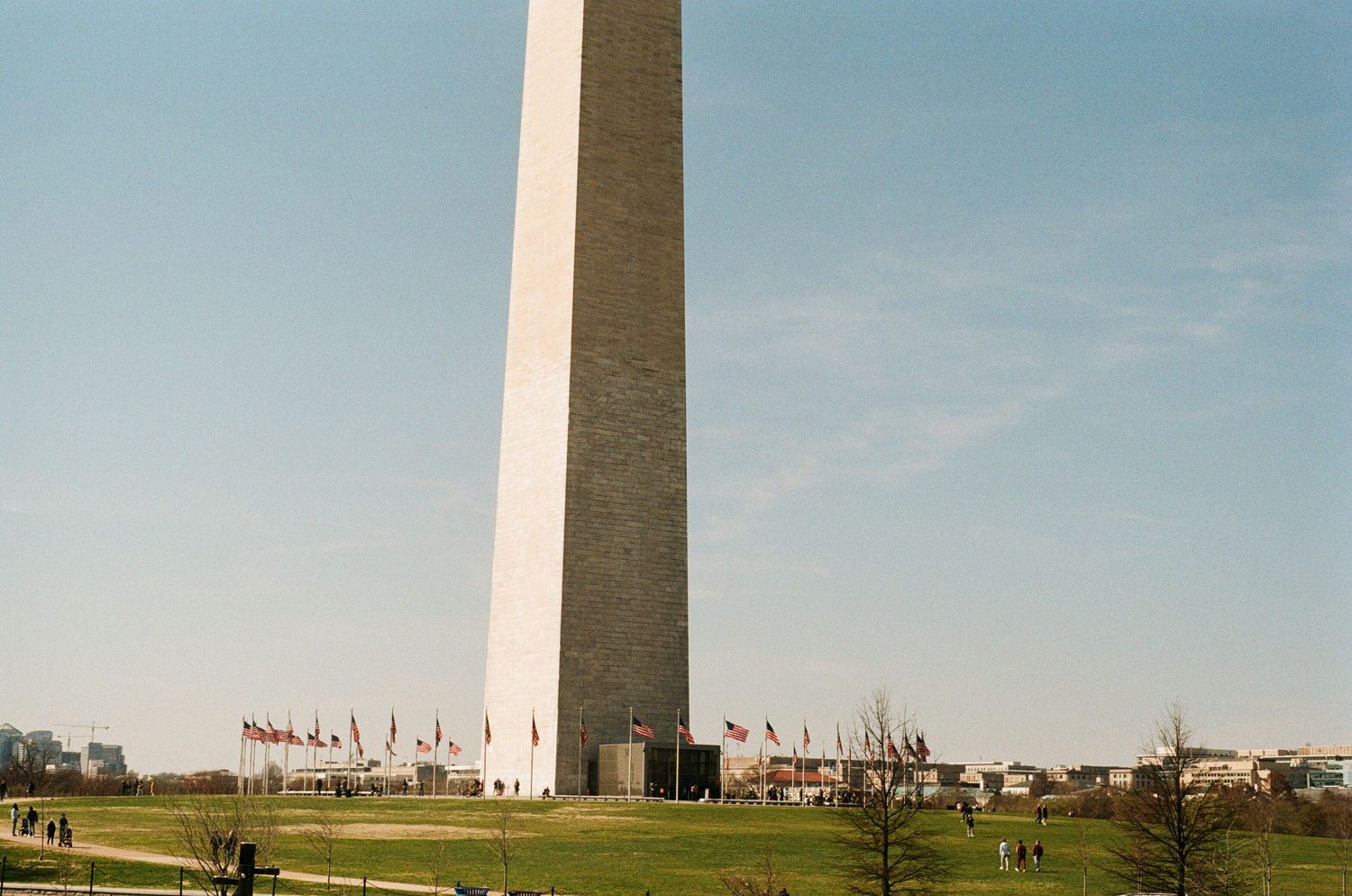 Washington Monument stands tall against a clear blue sky with surrounding buildings visible in the distance.