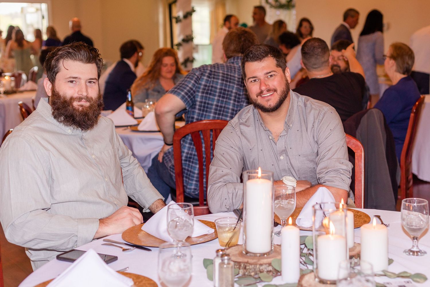 Wedding guests gathered around tables at an indoor reception venue with casual atmosphere.