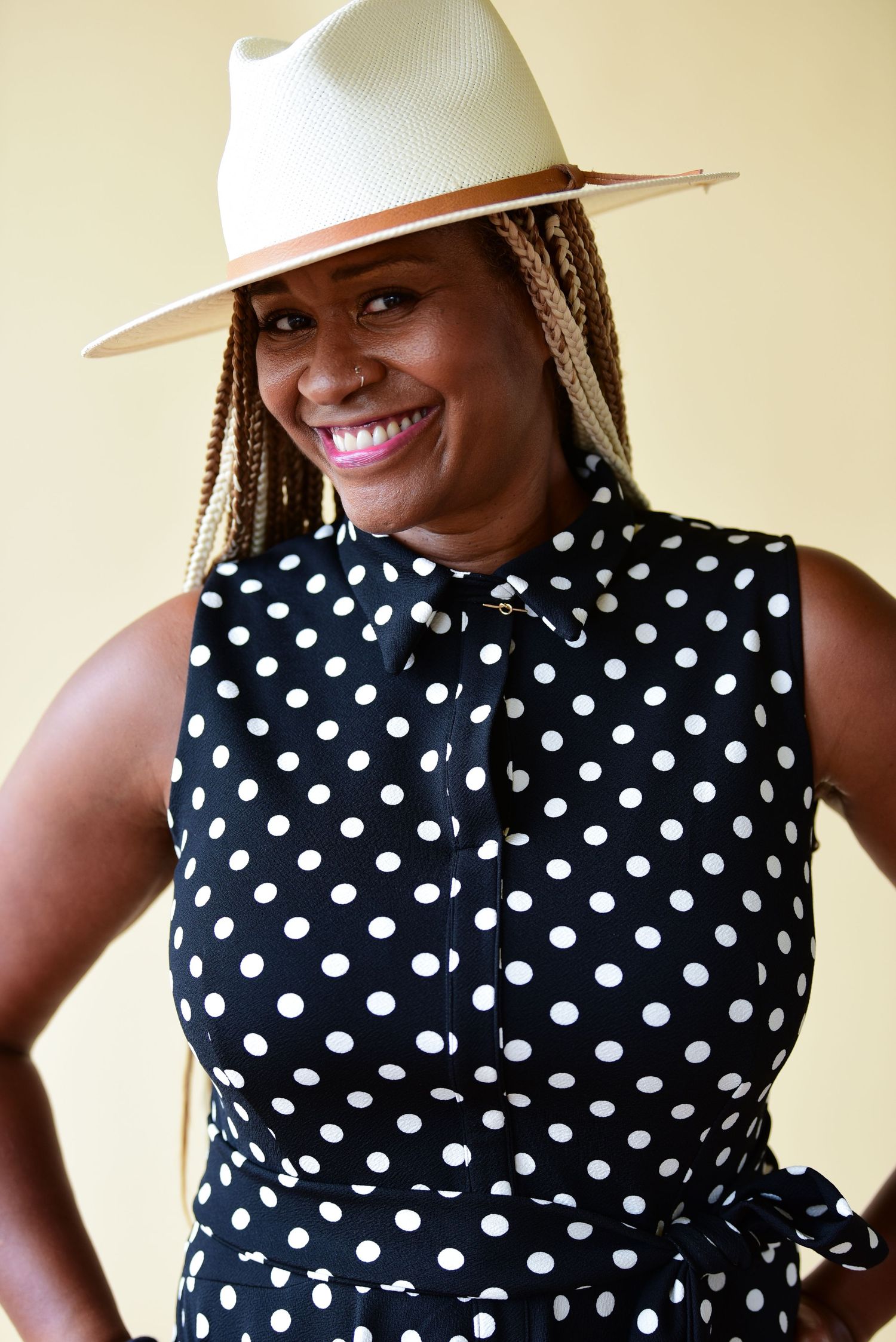 Stylish black and white polka dot sleeveless top paired with a crisp white wide-brim hat.