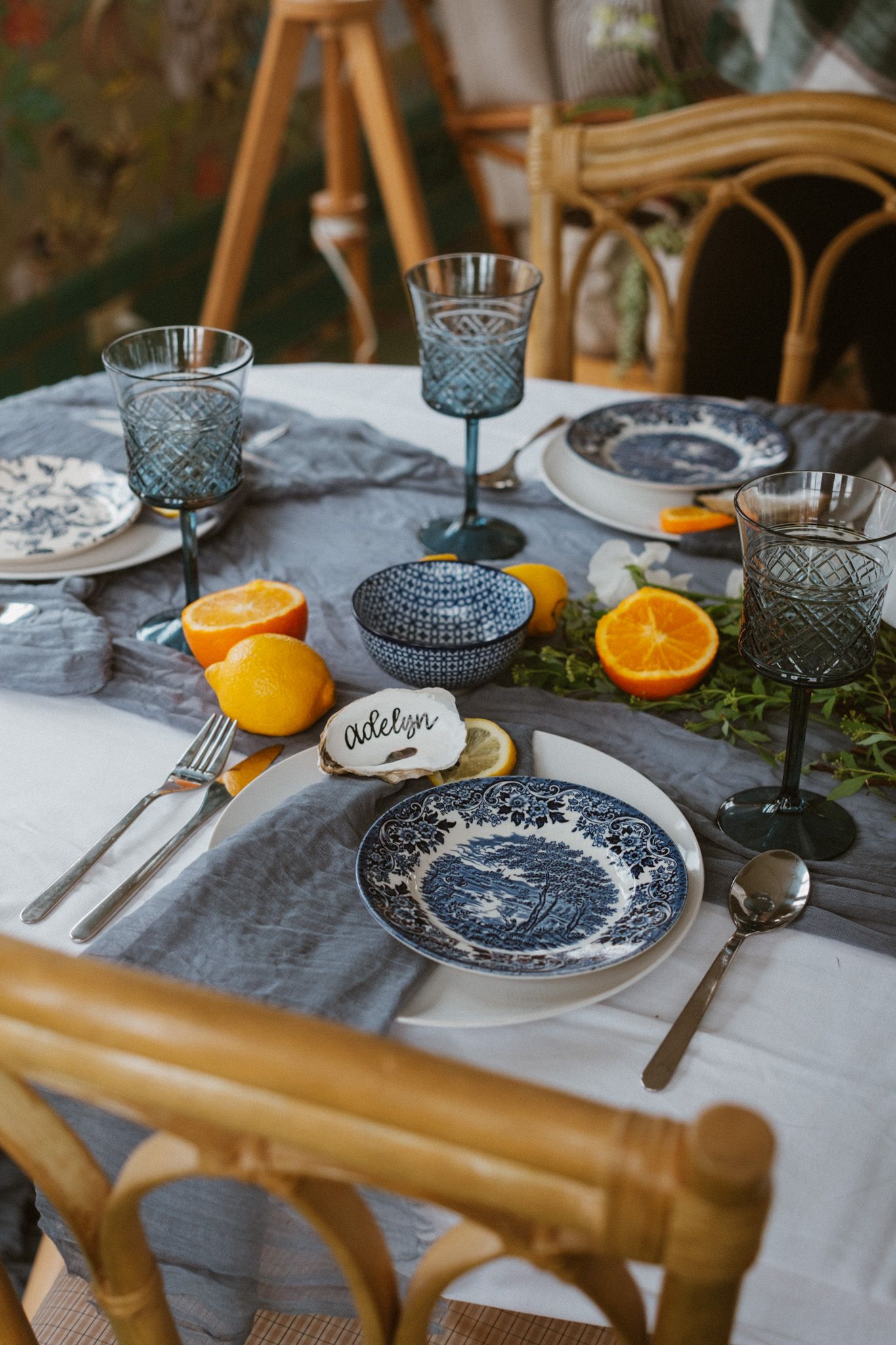 Elegant table setting with blue and white plates, orange slices, and crystal glasses on a white tablecloth.