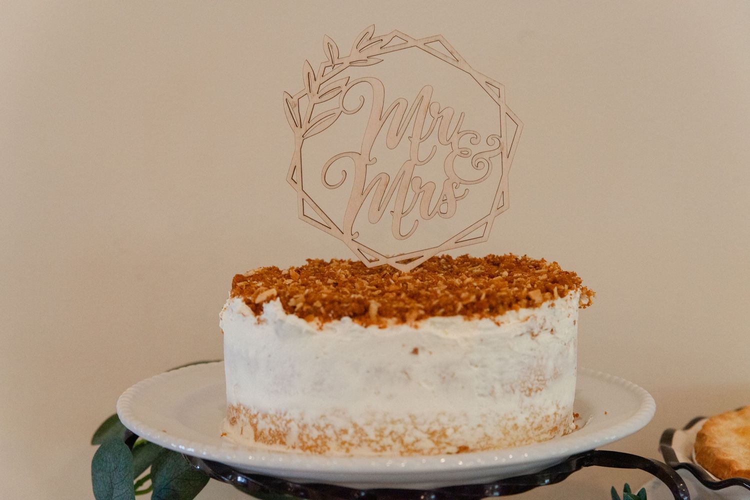 White wedding cake with delicate floral design and golden accents on display.