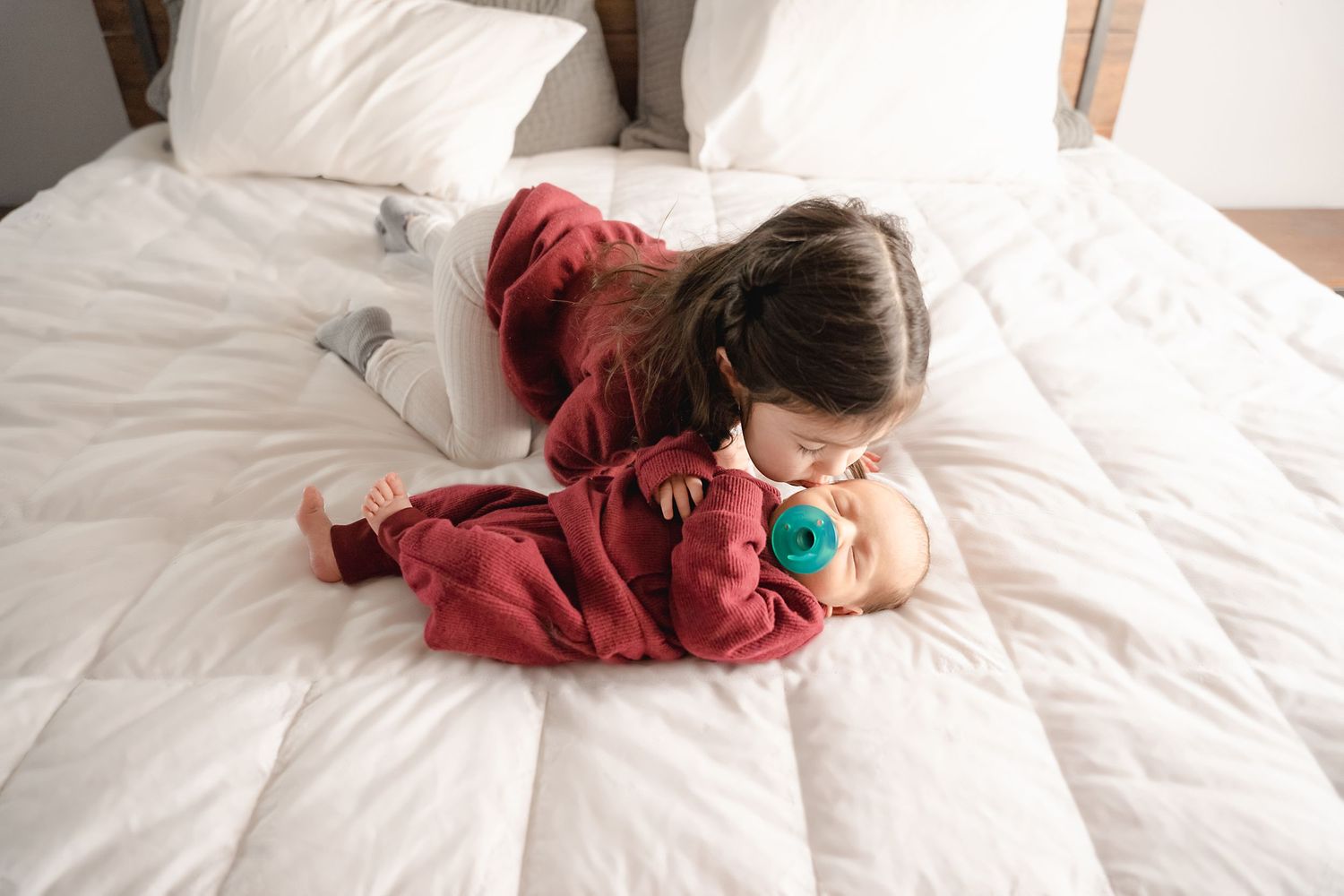 big sister giving baby brother a kiss on the cheek during session with Raleigh Newborn Photographer