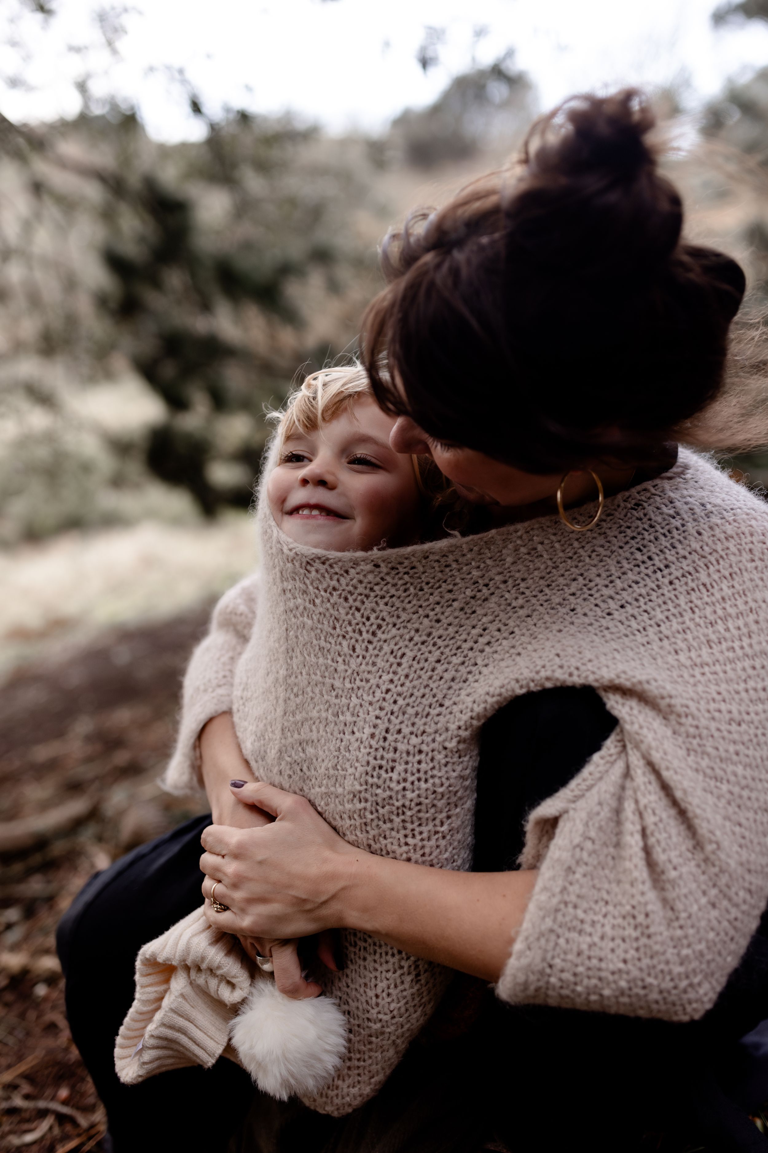 A tender embrace captured in warm tones showing affection between two people wearing knit sweaters.