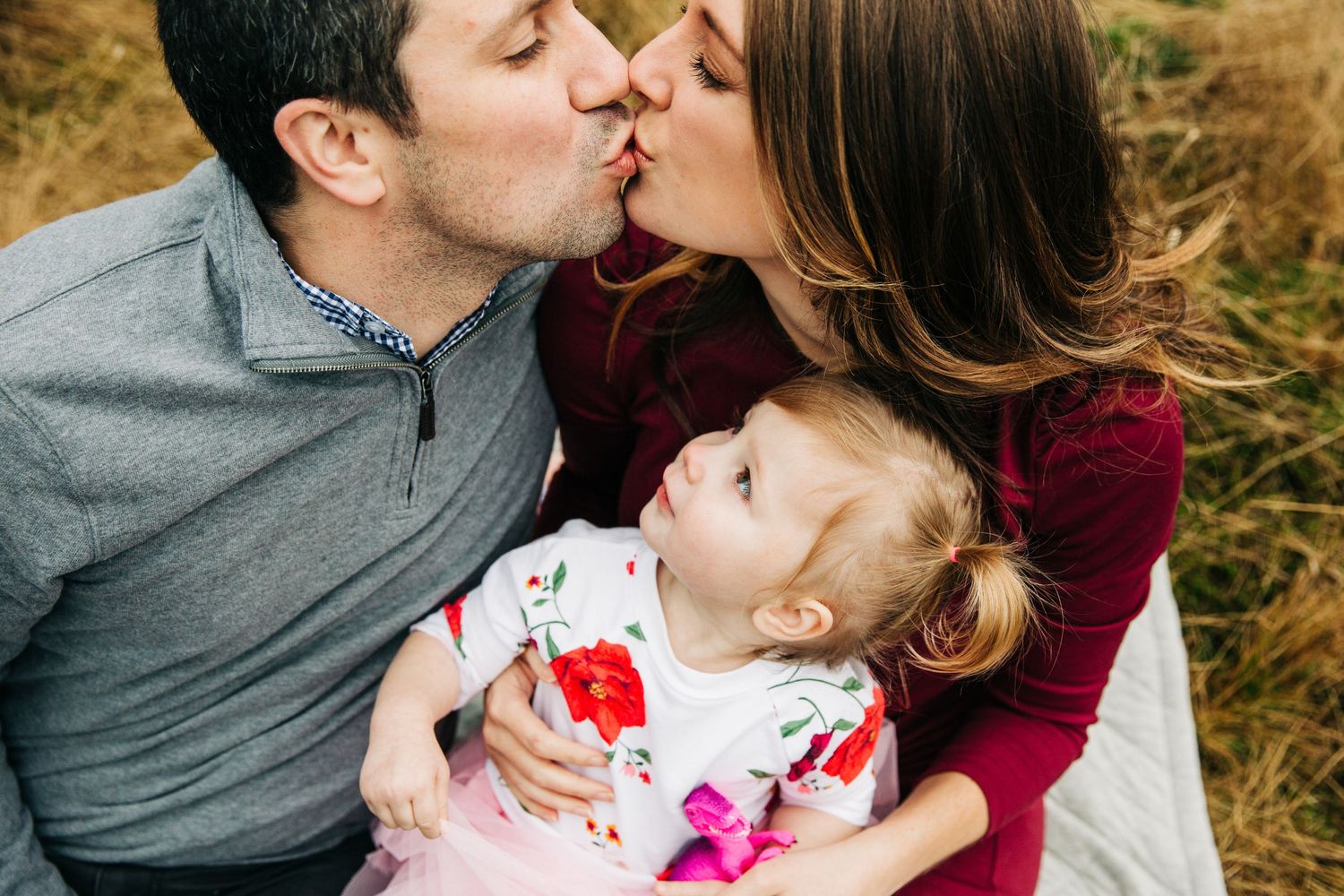 Close up of little girl looking up at her parents kissing