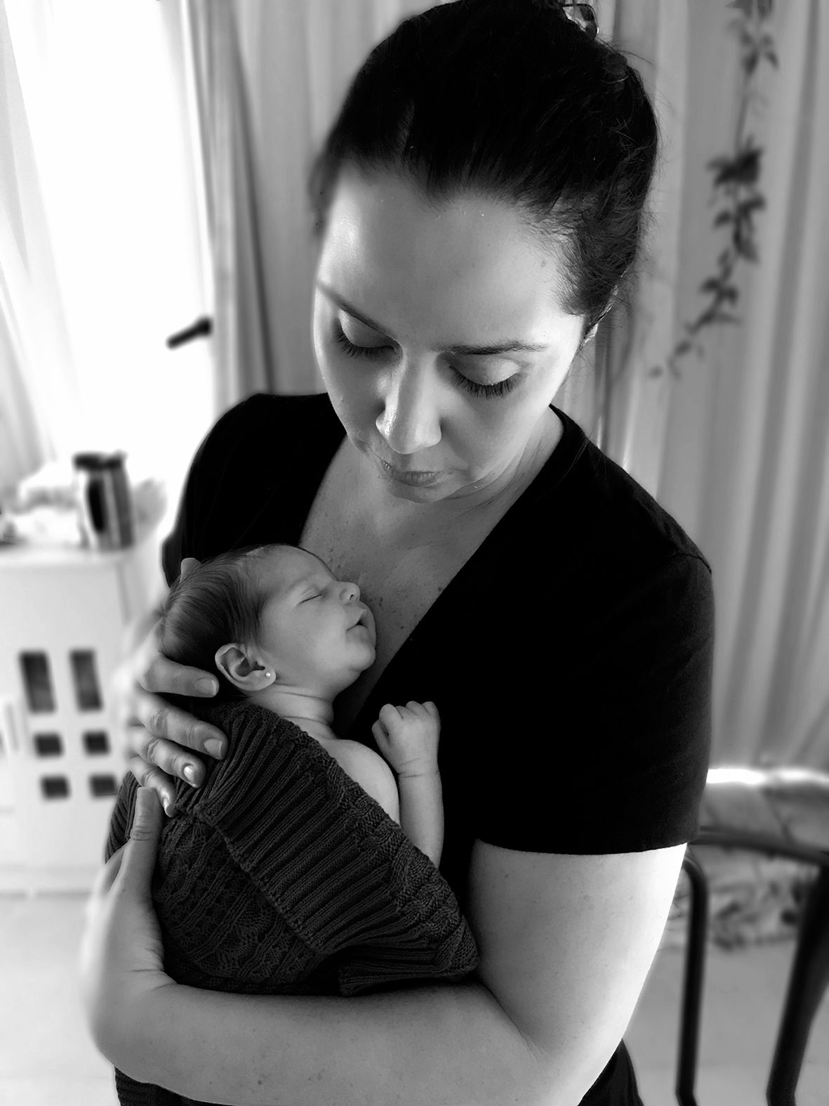 Black and white photo of a tender moment between parent and newborn.
