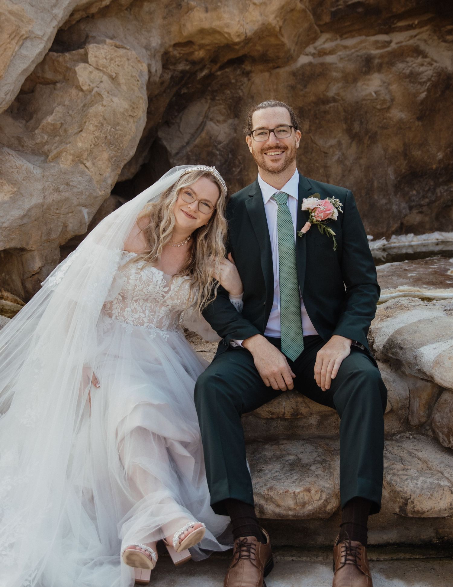 Bride and groom siting on steps and smiling at camera