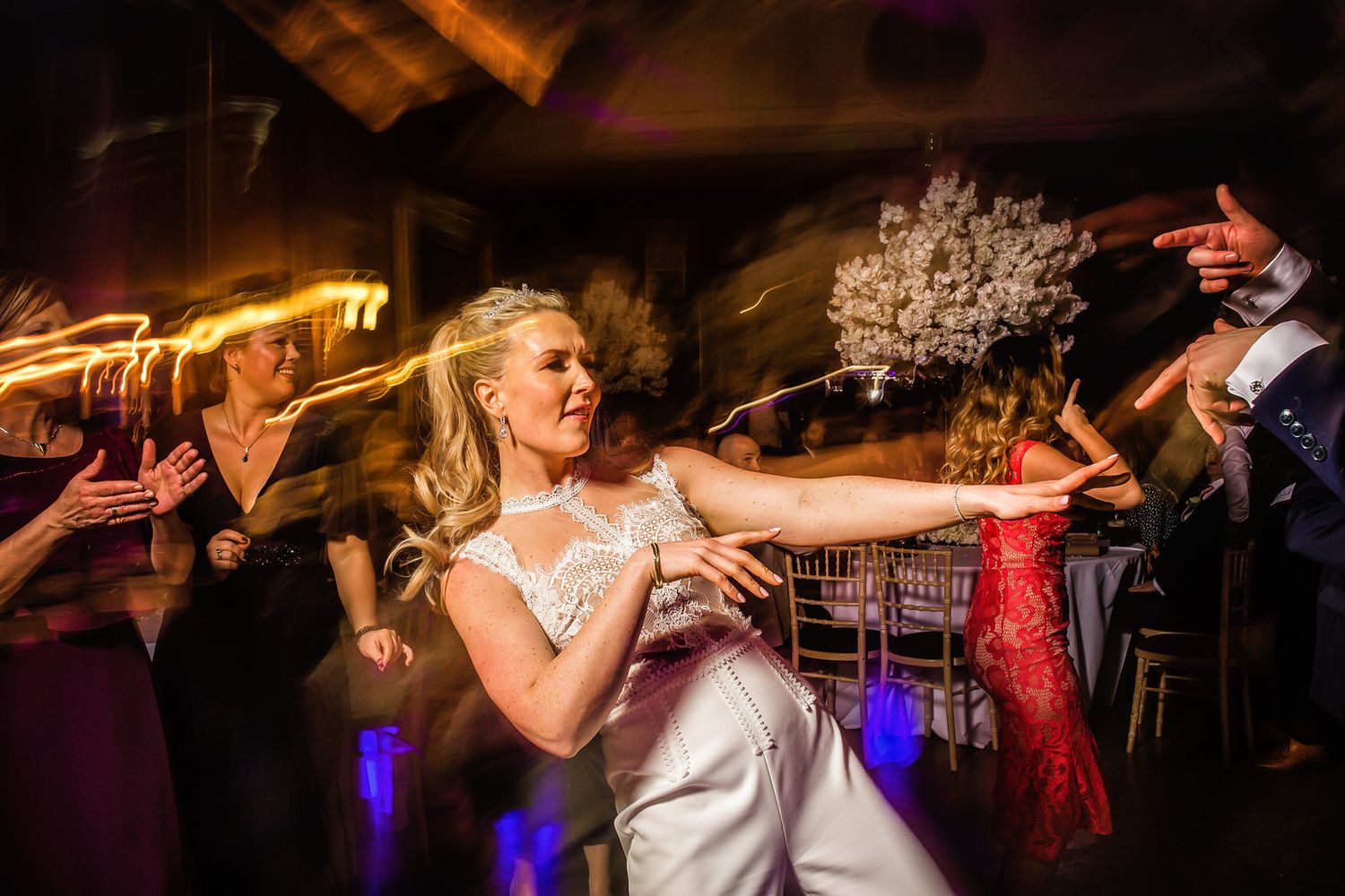 Energetic dance floor moment captured with warm lighting and motion effects at wedding reception.