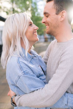 A close-up of a happy couple embracing and gazing at each other in warm sunlight outdoors.