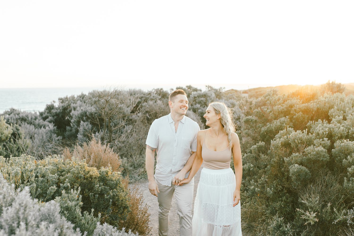 Romantic couple enjoying a sunset stroll together on a desert hiking trail surrounded by sage brush.