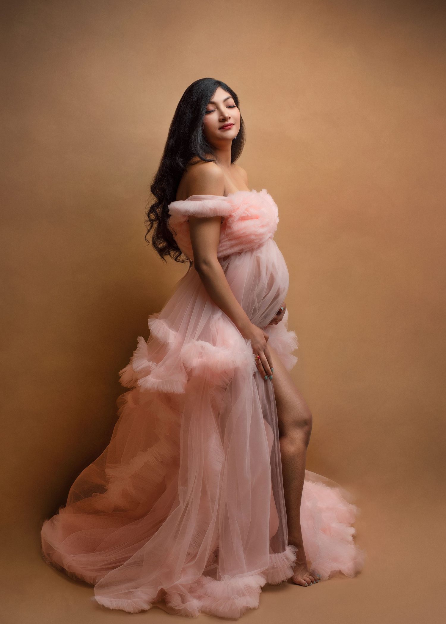 a pregnant mother smiles with her eyes closed during her maternity photos while wearing a cotton candy pink flowy dress