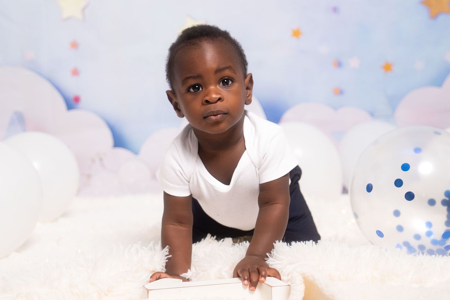 Child portrait session with ethereal star and cloud background in soft blue tones.