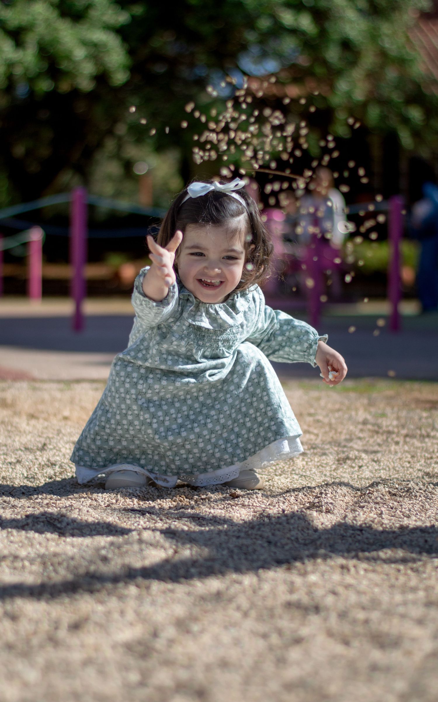 Child in polka dot dress playing with glitter in a playground.