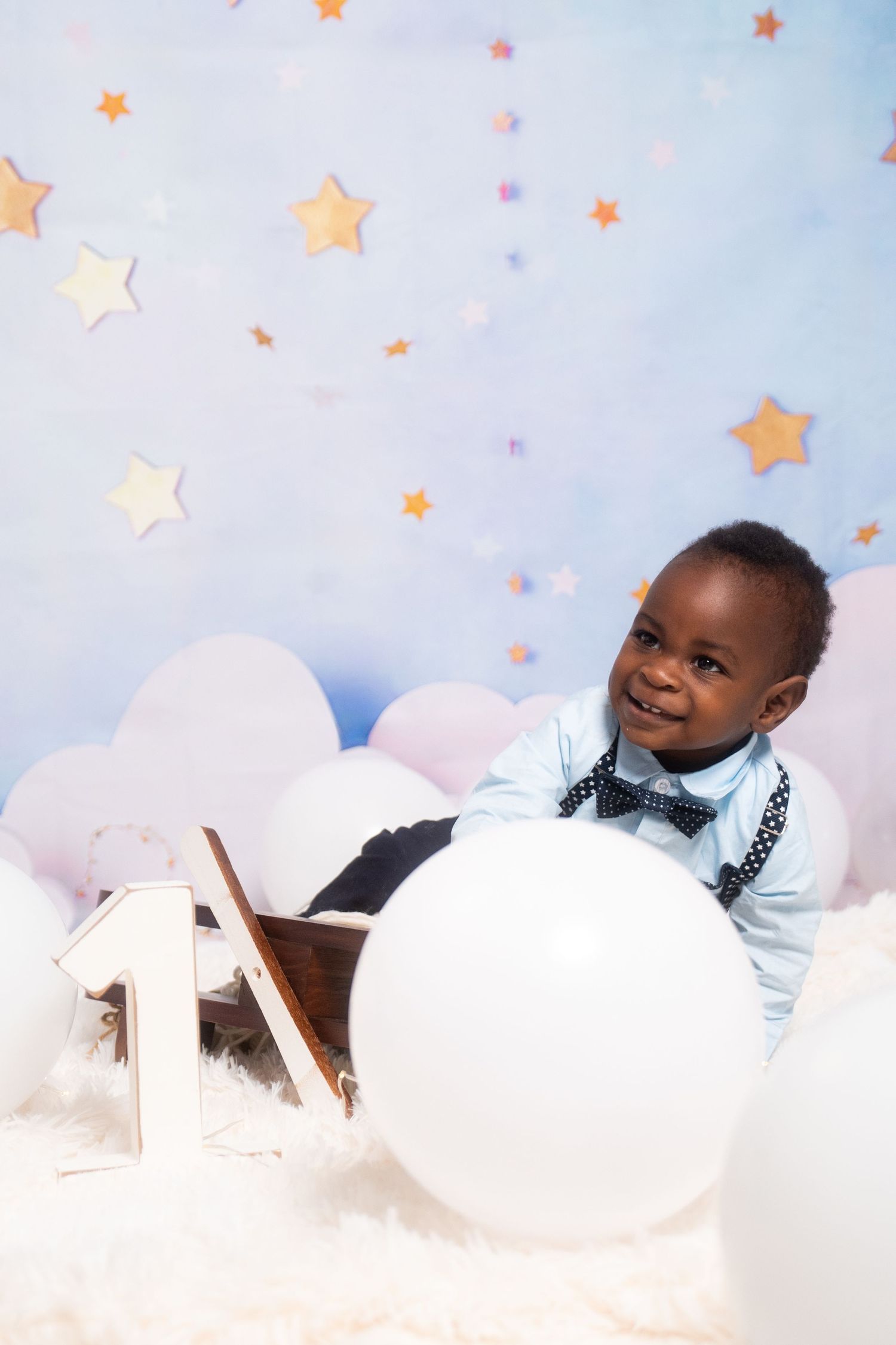 Whimsical children's photography setup with fluffy white clouds and golden stars.