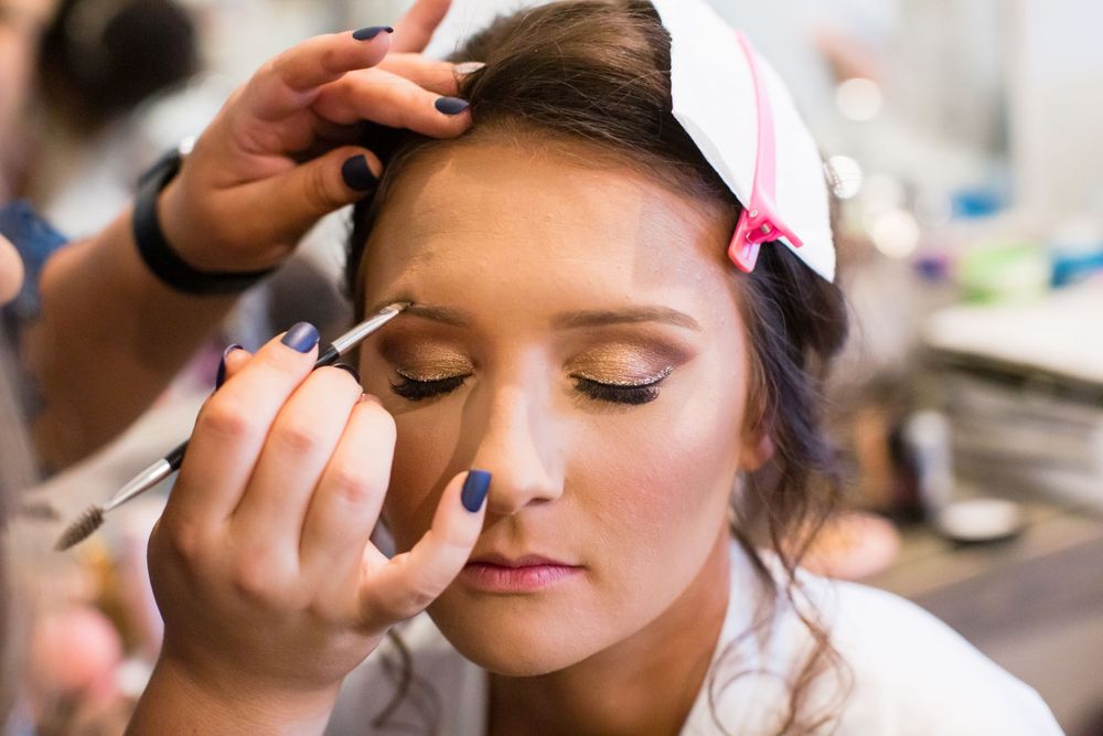Close-up shot of bridal makeup application showing eyeshadow being applied.