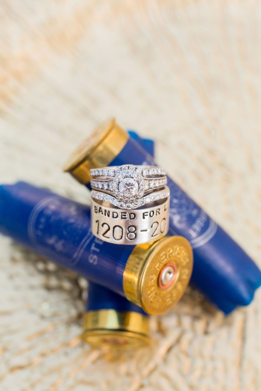 Wedding rings displayed on blue shotgun shells with engraved date details.