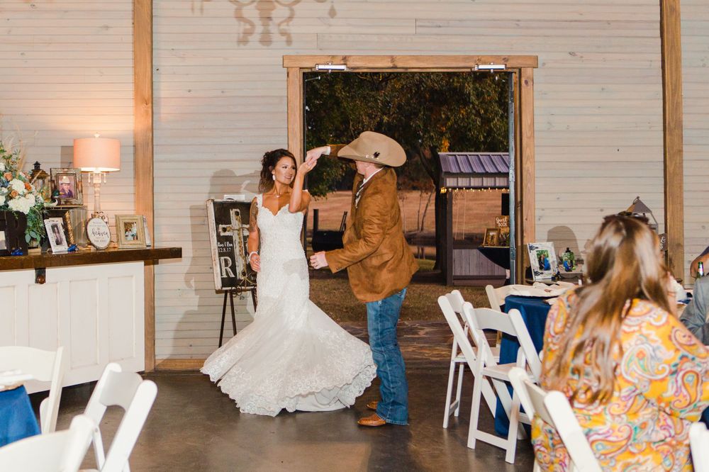 Dancing couple spins on rustic wooden dance floor during wedding reception.