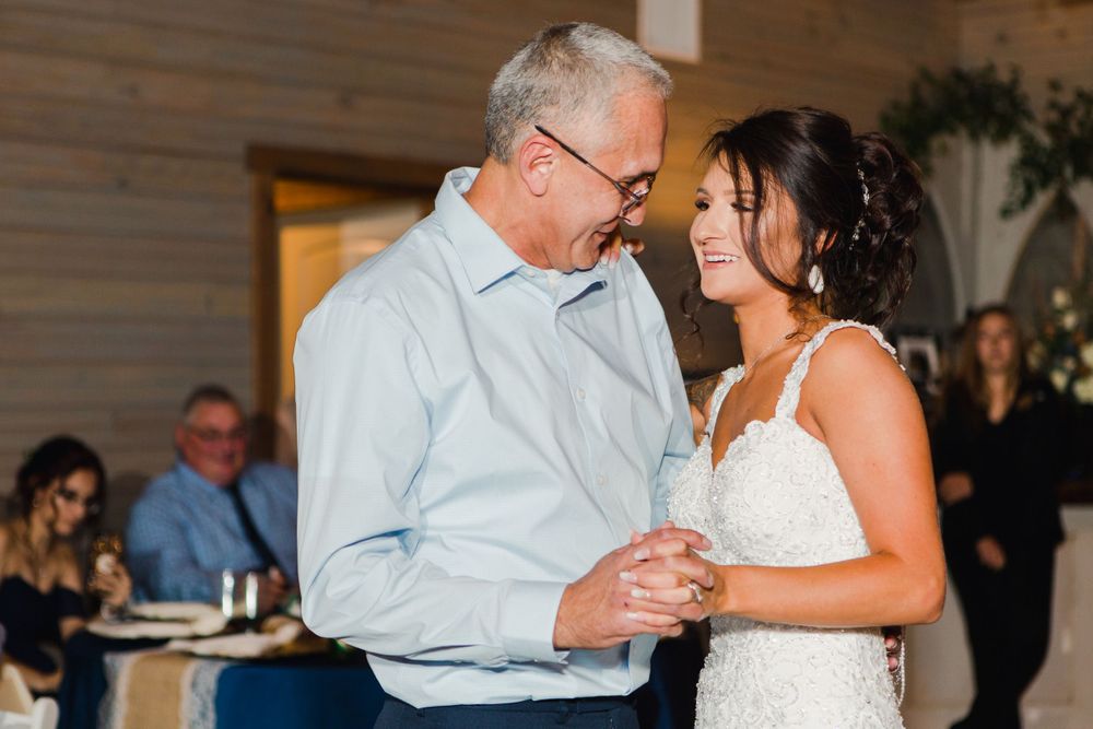 Tender moment shared during reception dance in rustic barn venue.