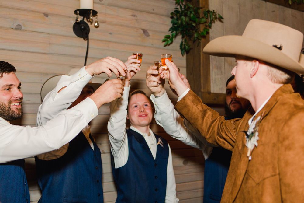 Wedding guests raise shot glasses together in a celebratory toast.