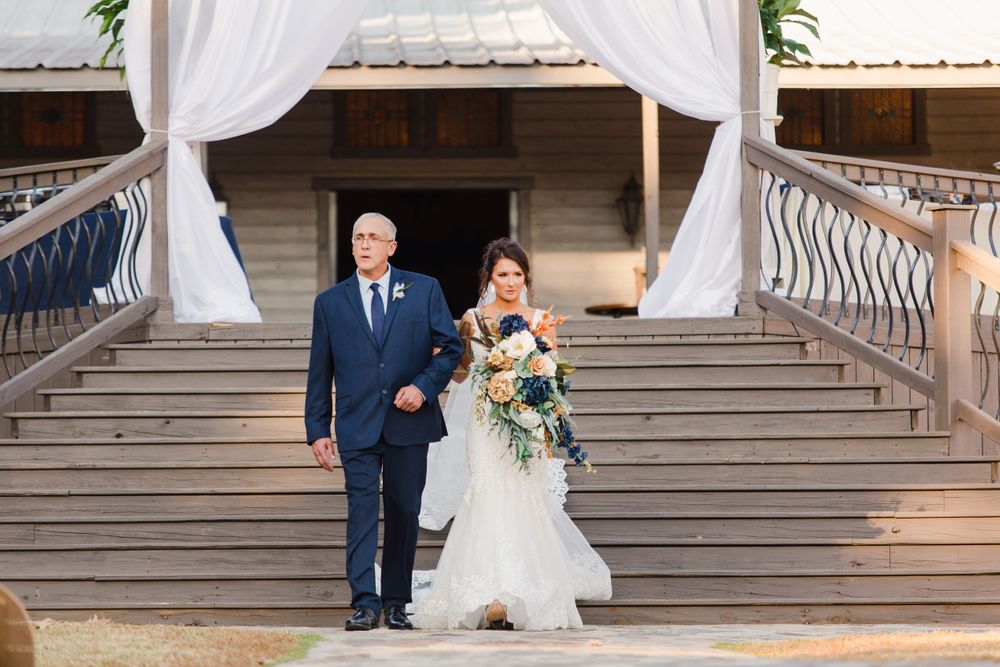 Couple descending grand staircase under white draping at wedding venue.