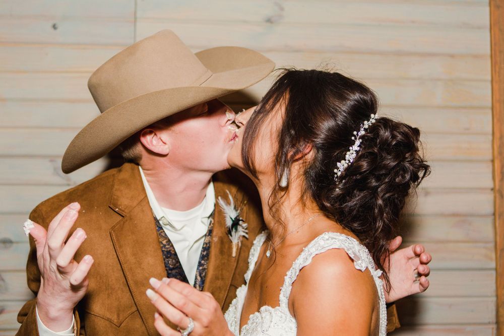 A tender moment between newlyweds in western attire at their reception.