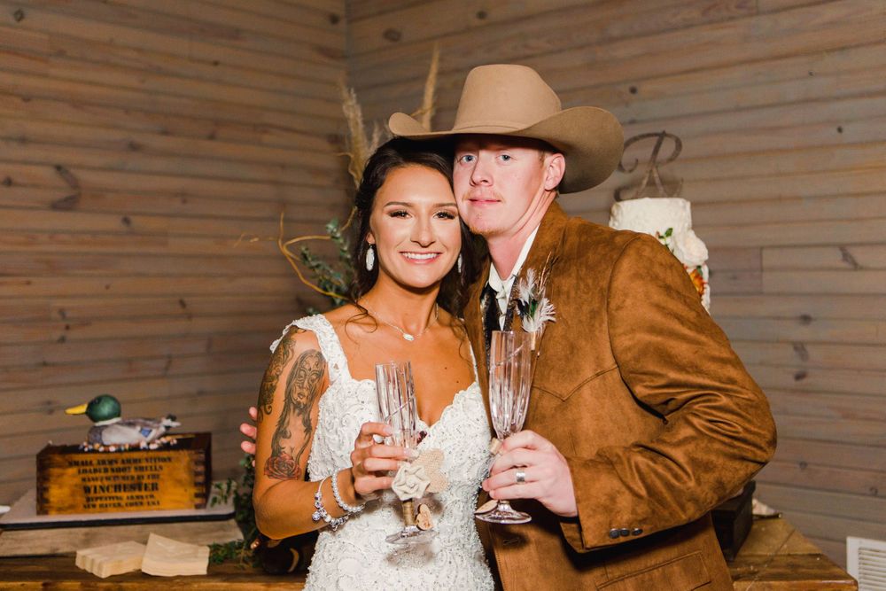 A couple in western wedding attire shares champagne during their reception.