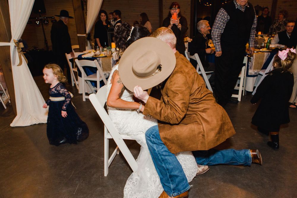 A playful moment during the wedding reception with western-themed attire.