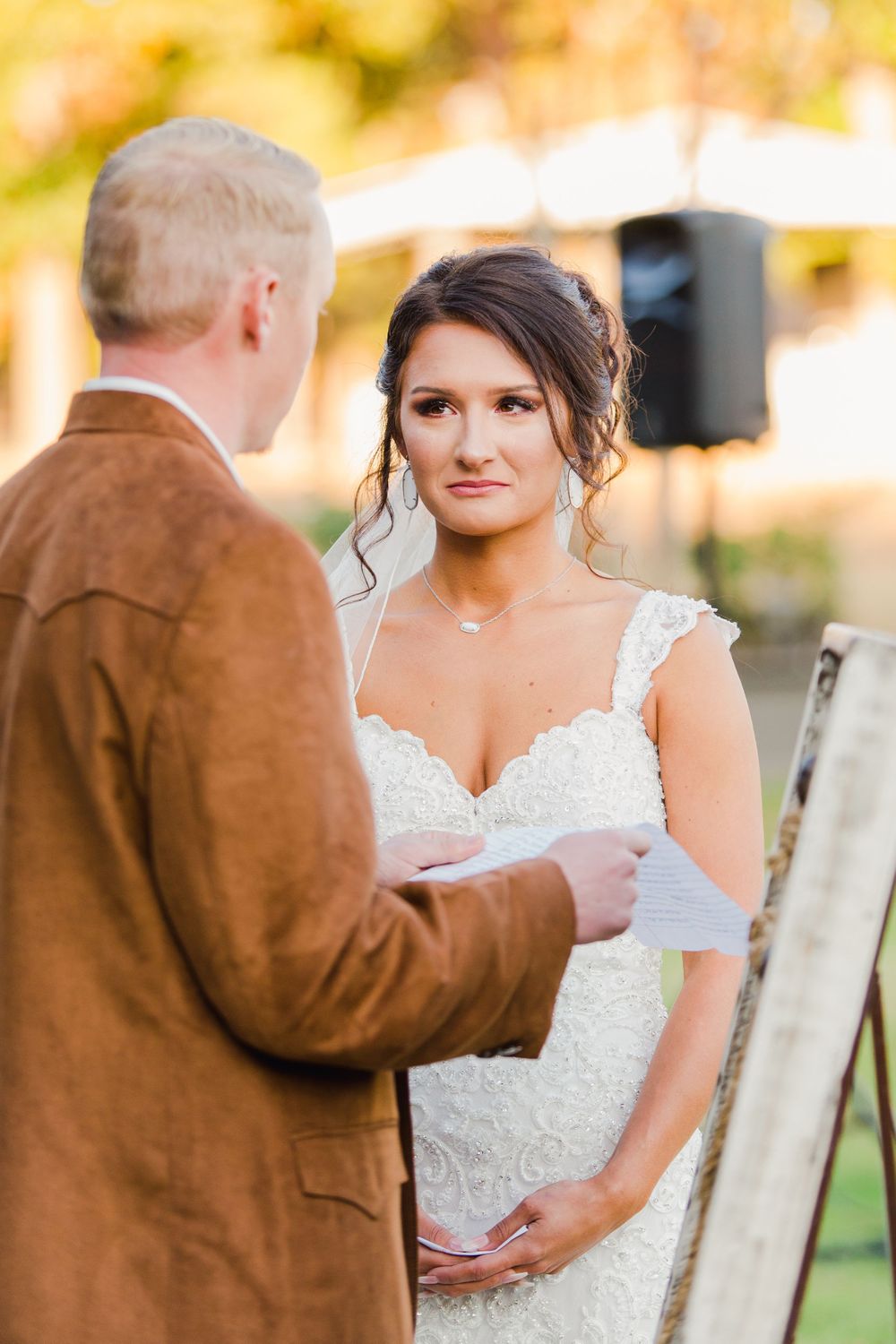Intimate wedding ceremony moment during vow exchange under autumn sunlight.