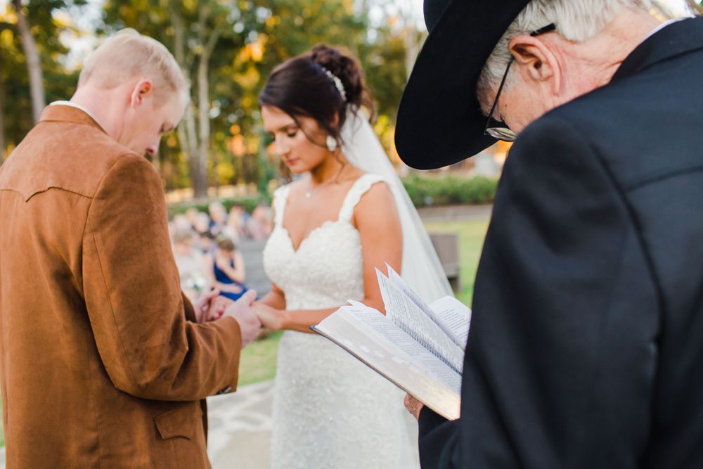 Wedding ceremony vow reading moment with officiant in black hat.