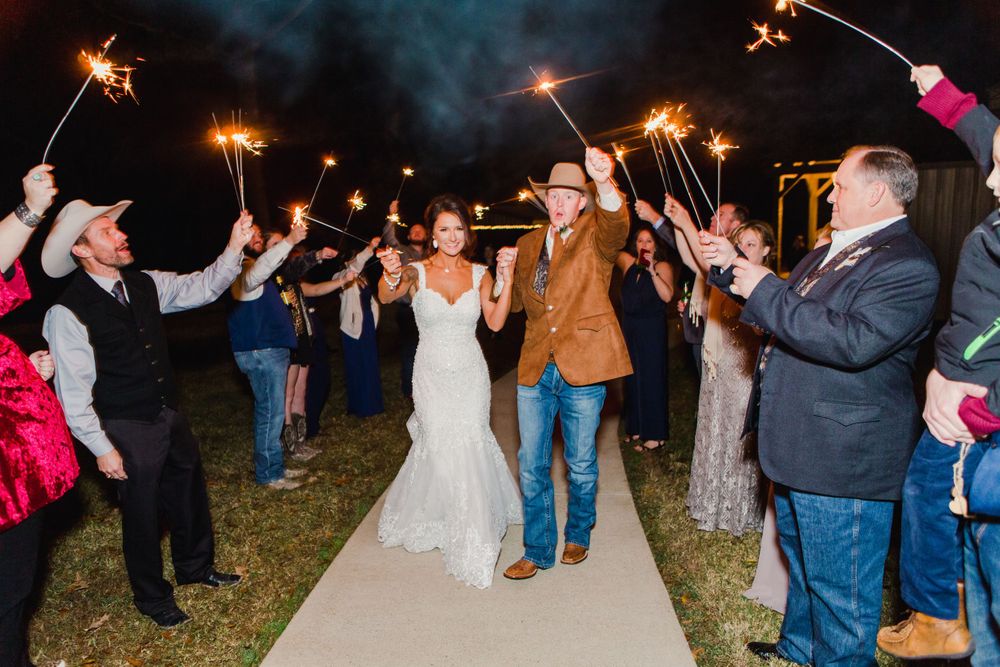 Wedding party celebrates with sparklers during a nighttime send-off celebration.