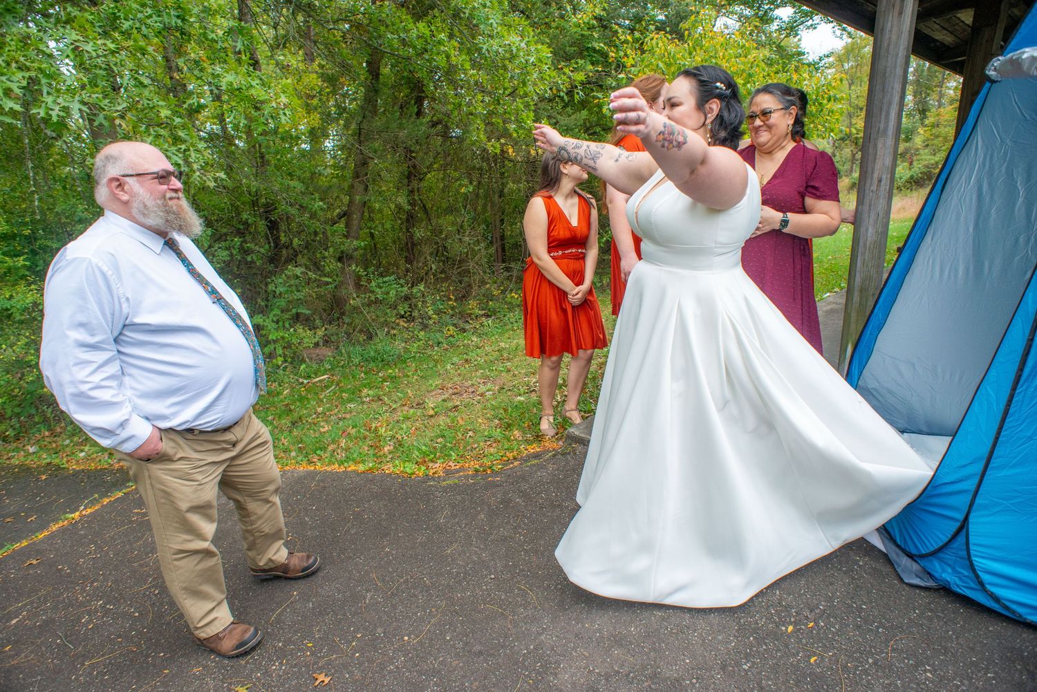 A joyful wedding celebration outdoors with a white dress twirling against a green forest backdrop.