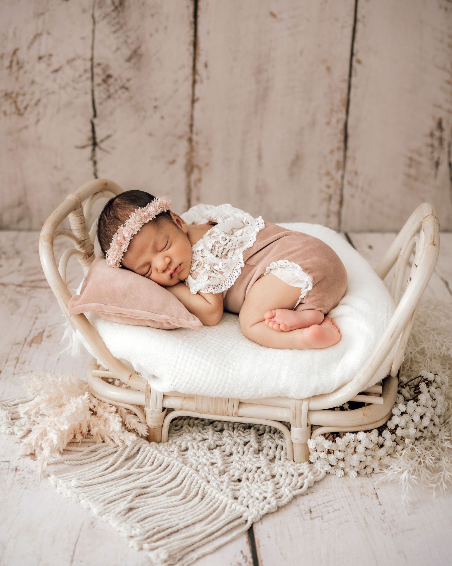 Sleeping newborn on rattan bed with lace romper and headband. Professional newborn photographer, Townsville, QLD, Australia.