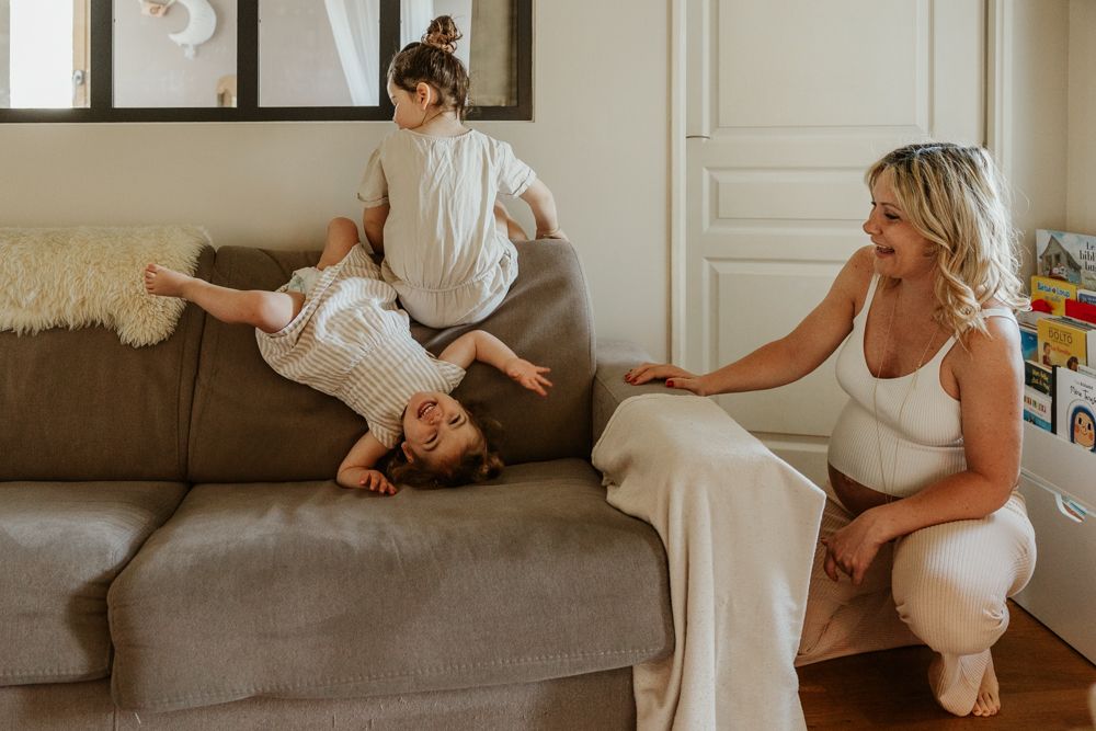 petites filles font les folles sur le canapé pendant une séance photo grossesse en famille à Lille