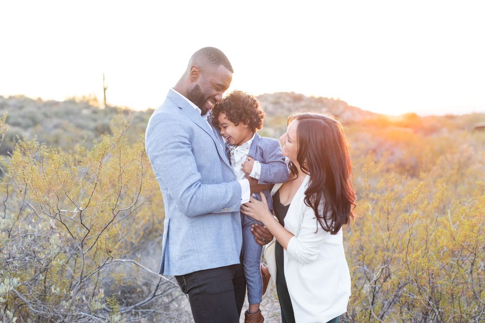 Family shares tender moment together in desert setting during sunset.