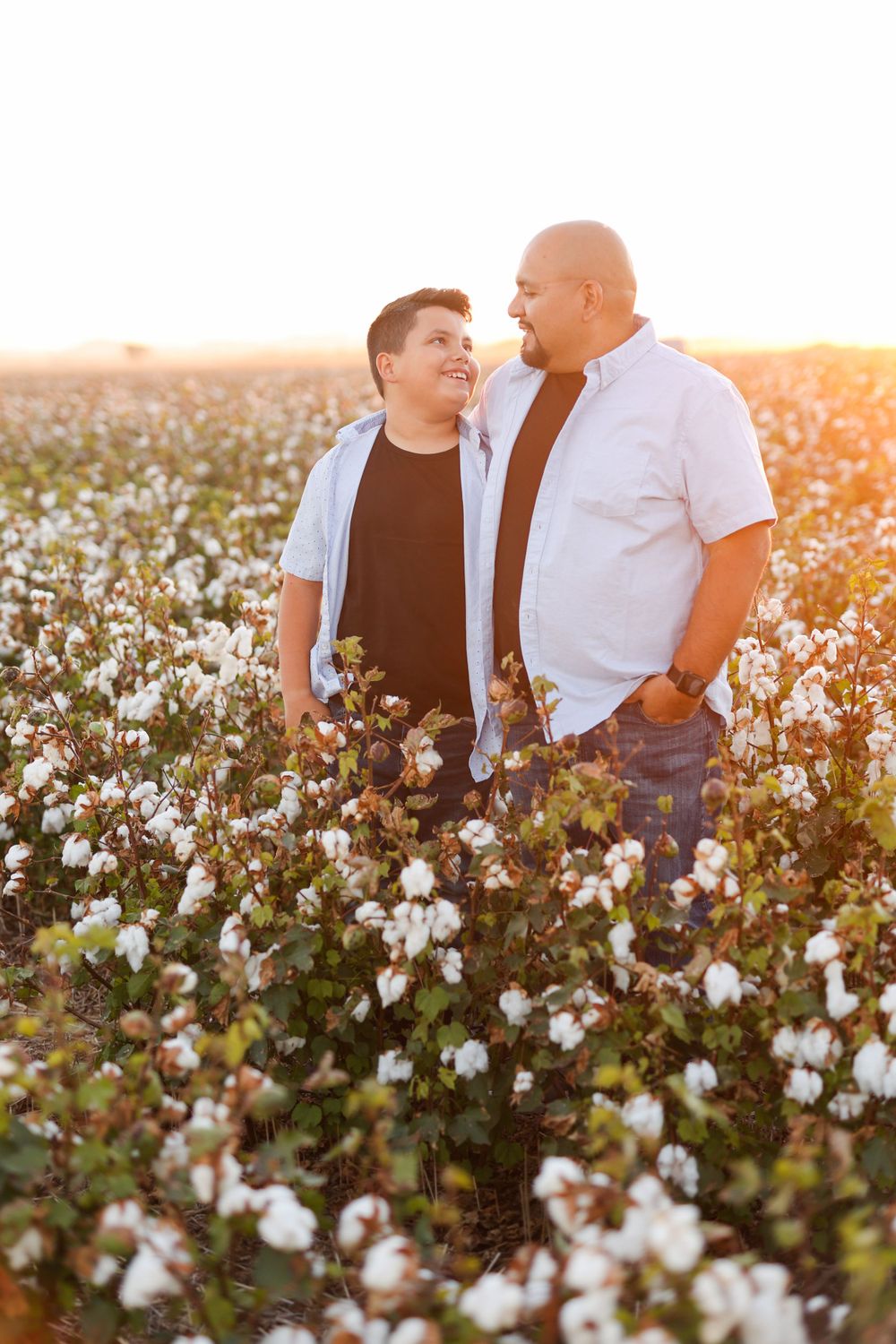 Intimate moment between two people standing in cotton field at sunset.